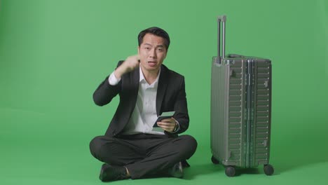 녹색 스크린 에 여권 과 수하물 을 가지고 앉아 있는 사업가