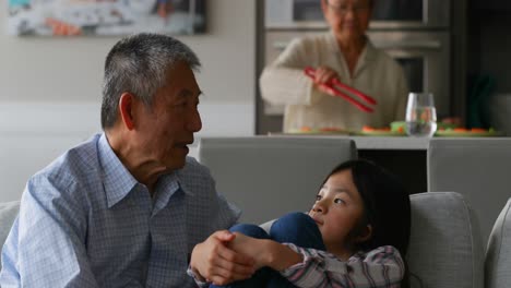 Front-view-of-cute-asian-granddaughter-interacting-with-her-old-senior-grandfather-at-home-4k