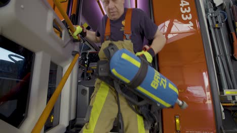 breathing apparatus being carried out of the fire truck by a firefighter