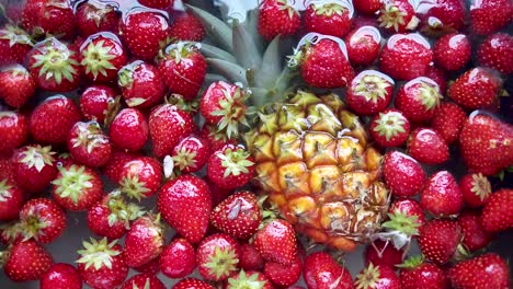 alejar detalle de piña fresca y fresas flotando en el agua
