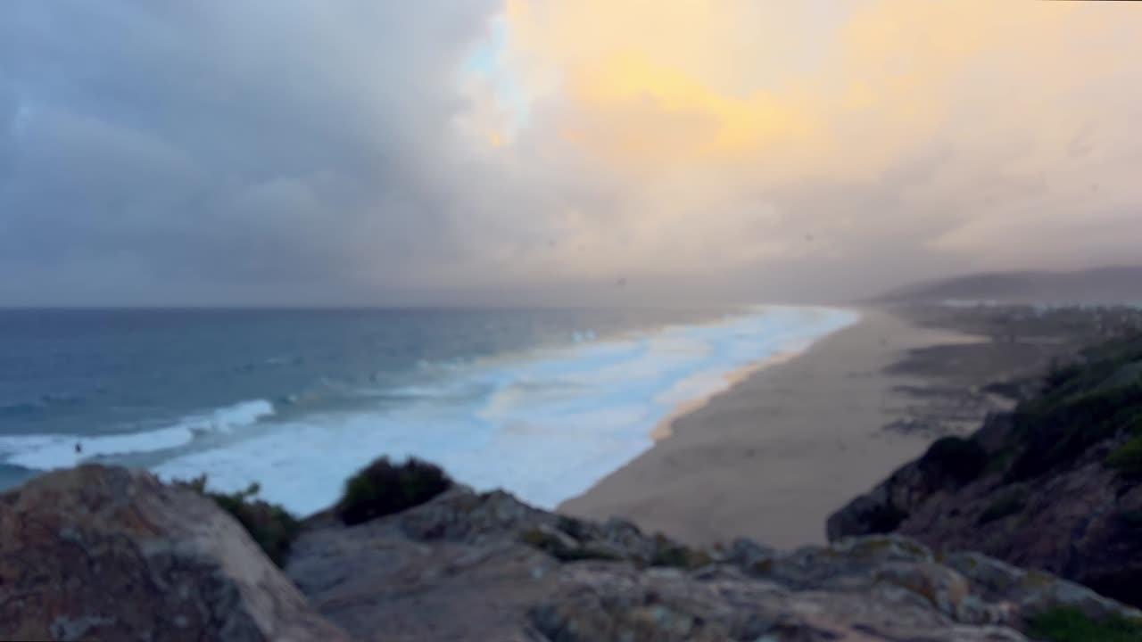 저녁 햇살 아래, 편안하게 휴식을 취하는 사람들이 잔잔한 파도를 즐기는 넓은 해변 풍경