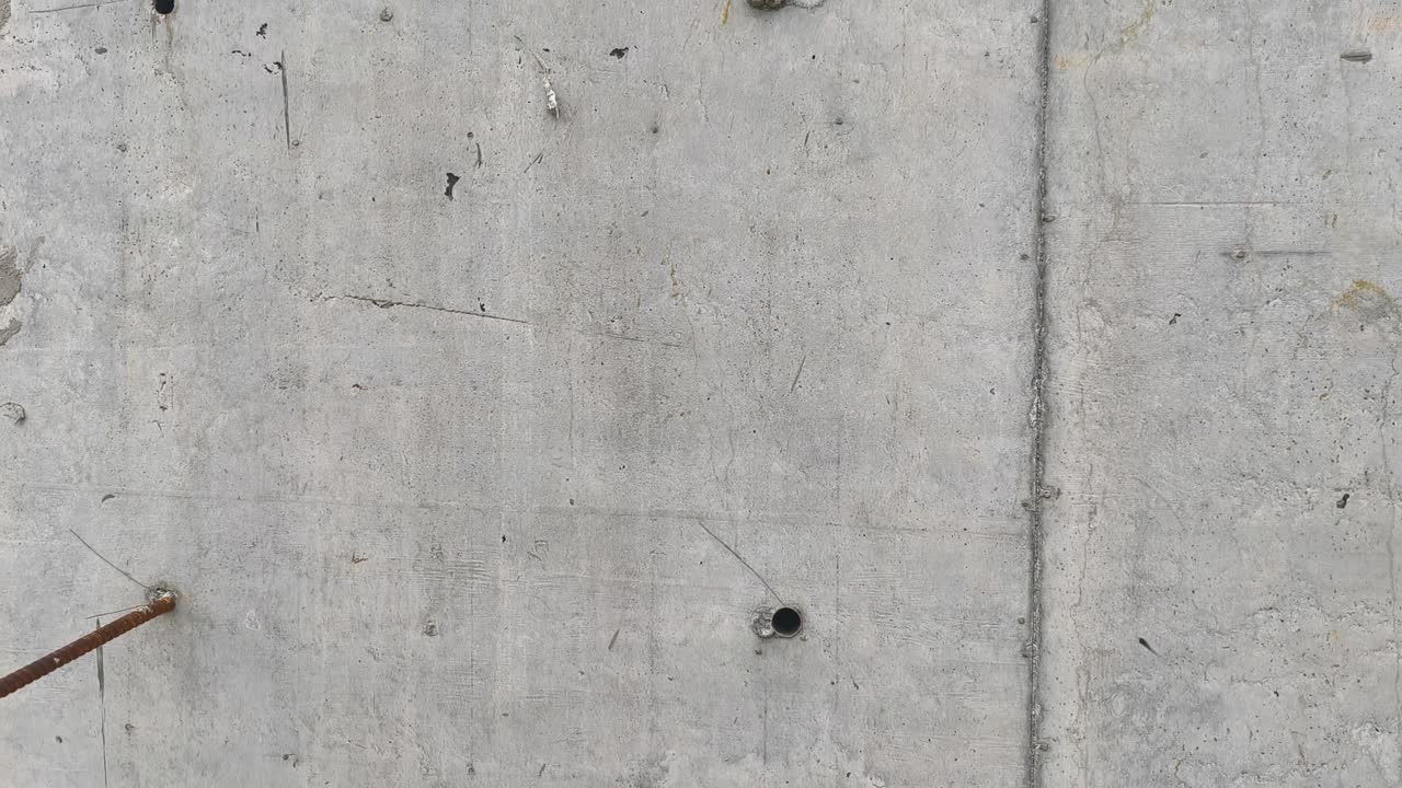 Den bare betonvægoverflade afslører en rå tekstur. Subtile detaljer fremhæver dens robuste karakter. En minimalistisk baggrund med industriel appel.