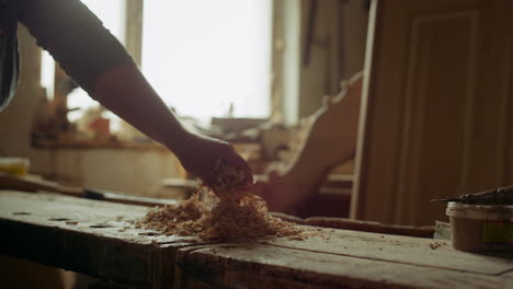 unknown man pouring sawdust indoors. man throwing sawdust in carpentry workshop