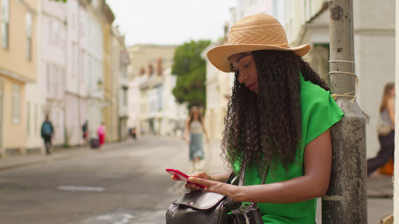 영국 옥스퍼드에서 휴가를 보내고 있는 여성 관광객이 홀리웰 스트리트를 따라 걸어가며 지침과 정보를 얻기 위해 휴대전화를 사용하고 있다.