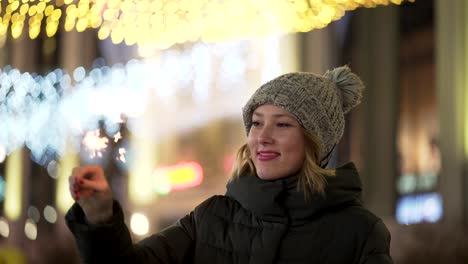 woman with sparkler on a city street at night during christmas