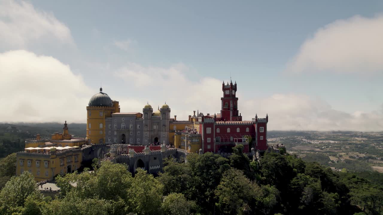 Cinematisch luchtkasteel, Paleis Pena in Sintra tegen een prachtige bewolkte blauwe lucht, uitzoomende luchtopname.