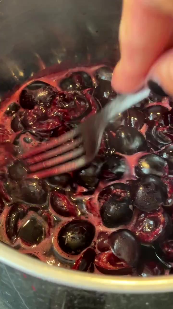 Mano che mescola ciliegie fresche in una pentola
