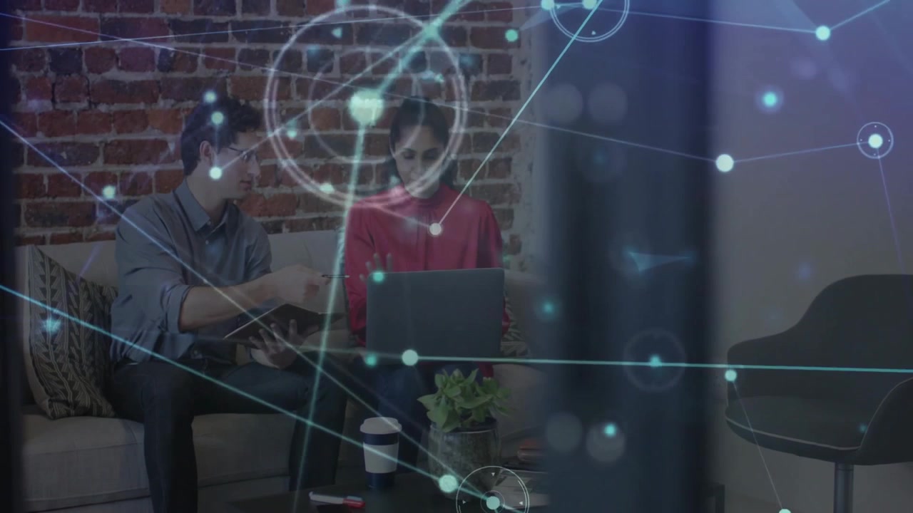 Tech colleagues pointing at notebook and opening laptop activating network overlay for project