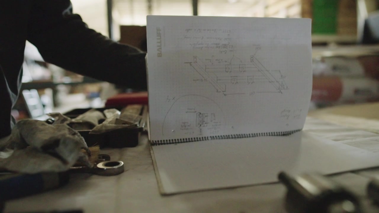 A slomo close up of a mechanic flipping through their building specs in their workshop
