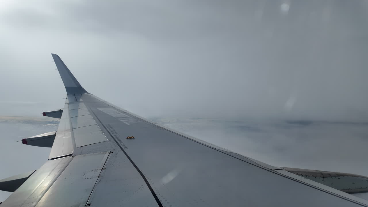 Aircraft wing gliding above layered clouds viewed from the window seat