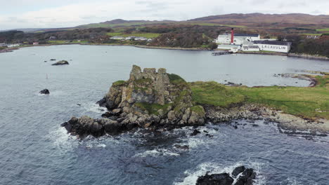 la destilería de whisky lagavulin aérea revelando detrás del castillo de dunivaig en el frente