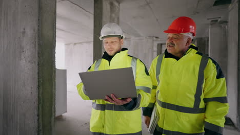 foreman-and-civil-engineer-are-walking-in-under-construction-building-portrait-of-two-builders