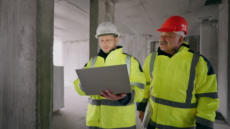 foreman and civil engineer are walking in under-construction building portrait of two builders