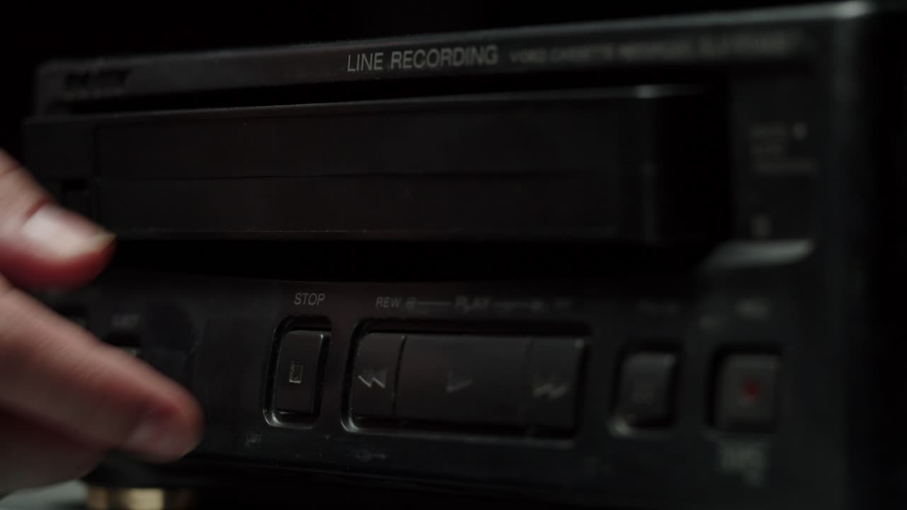 Hånd der skubber VHS-kassette ud af en vintage VCR-afspiller