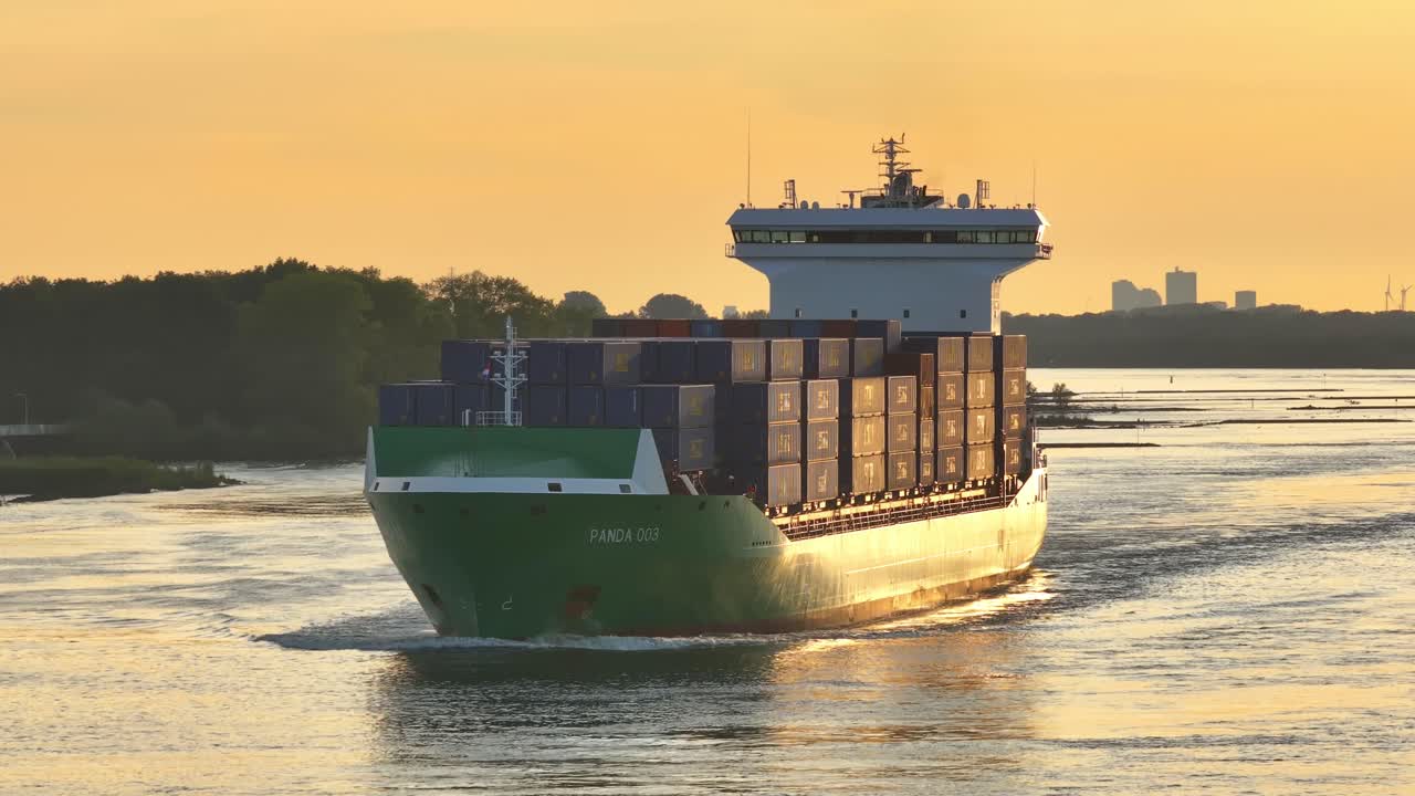 Large cargo ship 'PANDA 003' sailing on a waterway at sunset