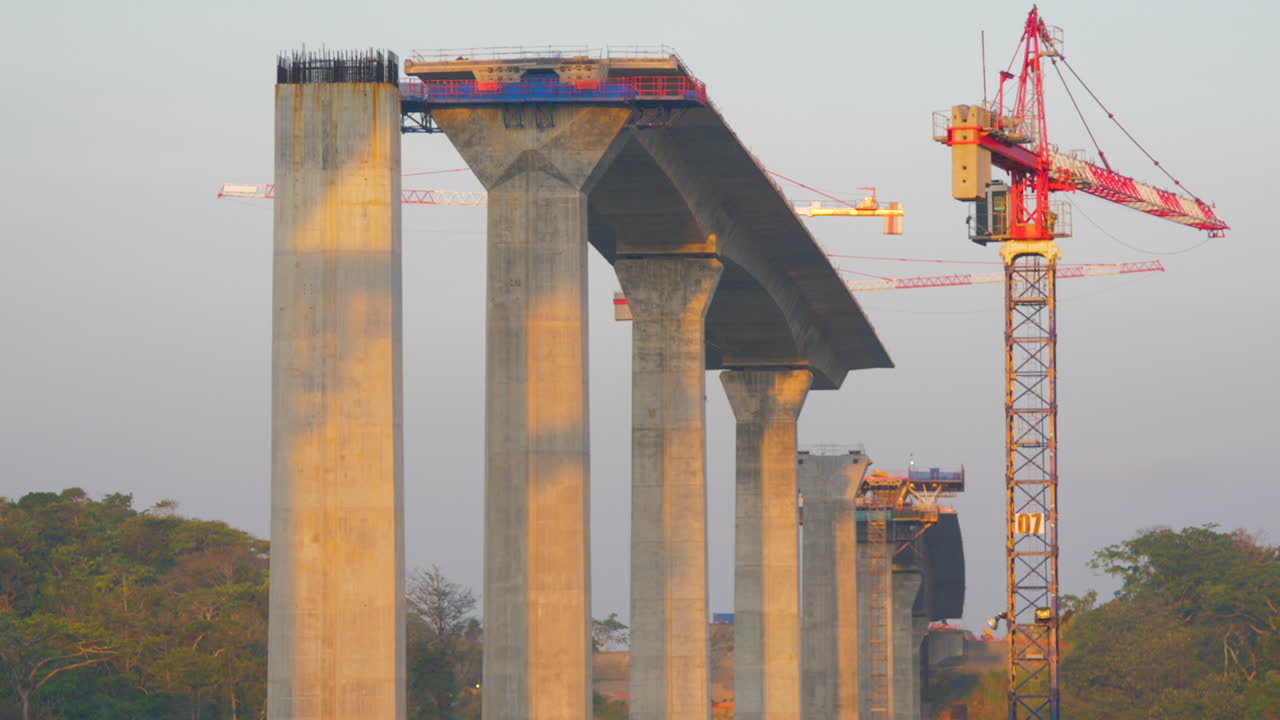 Big highway bridge over river under construction viewed from vessel passing by in late afternoon