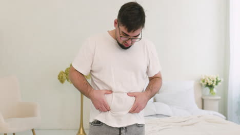 boy grabbing his belly fat in the bedroom