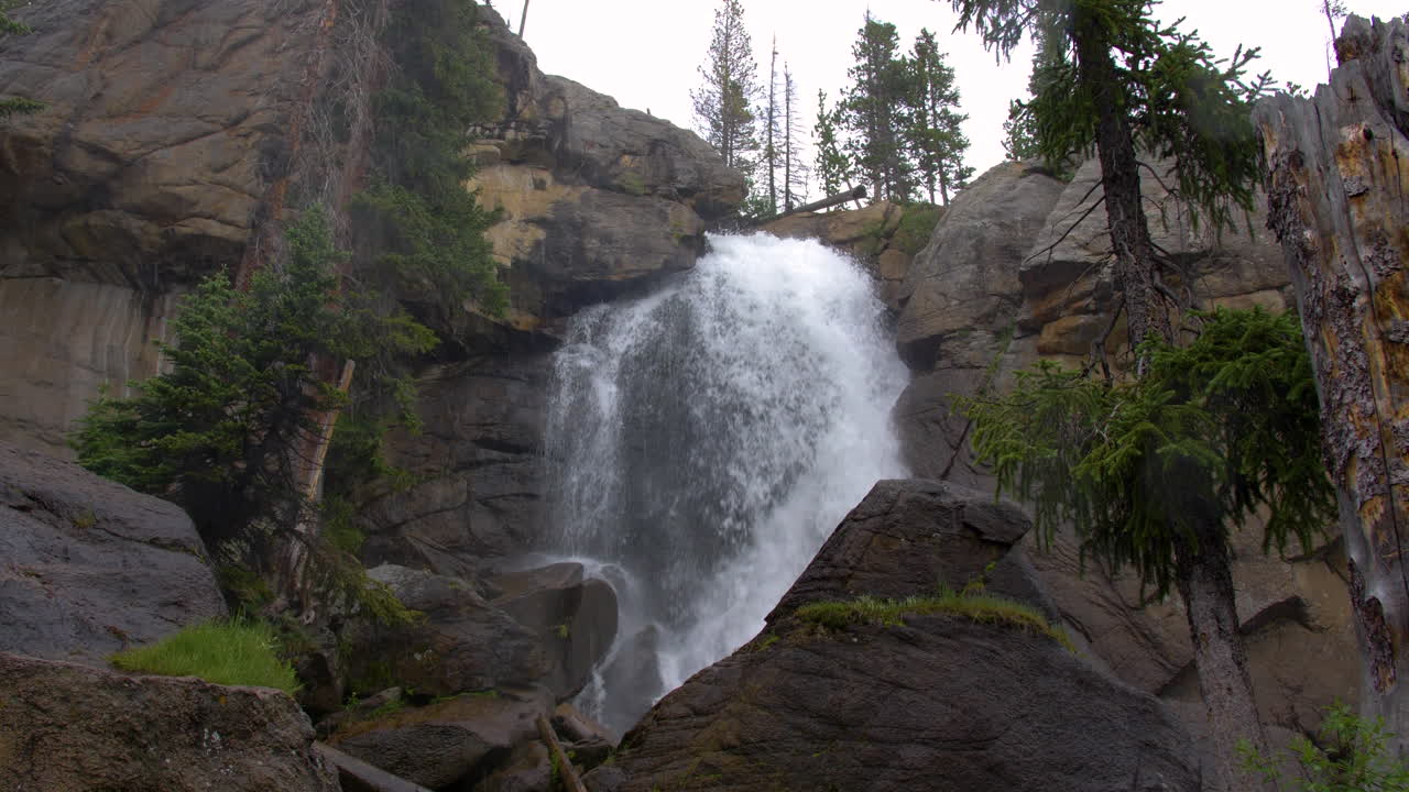 gran cara de granito con cascada que fluye en condiciones de nieve en montañas rocosas