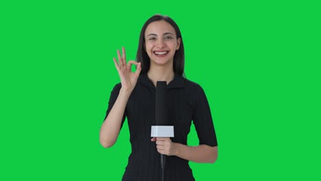 Happy-Indian-female-news-reporter-showing-okay-sign-Green-screen