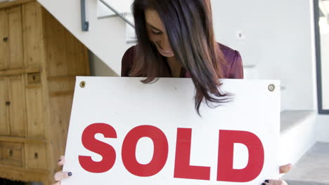 mujer sosteniendo un cartel que dice vendido