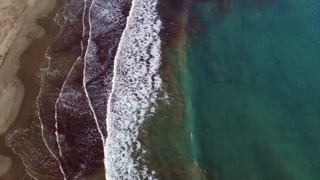 seaside lagoon waves foam, sea water with algae, top-down aerial view