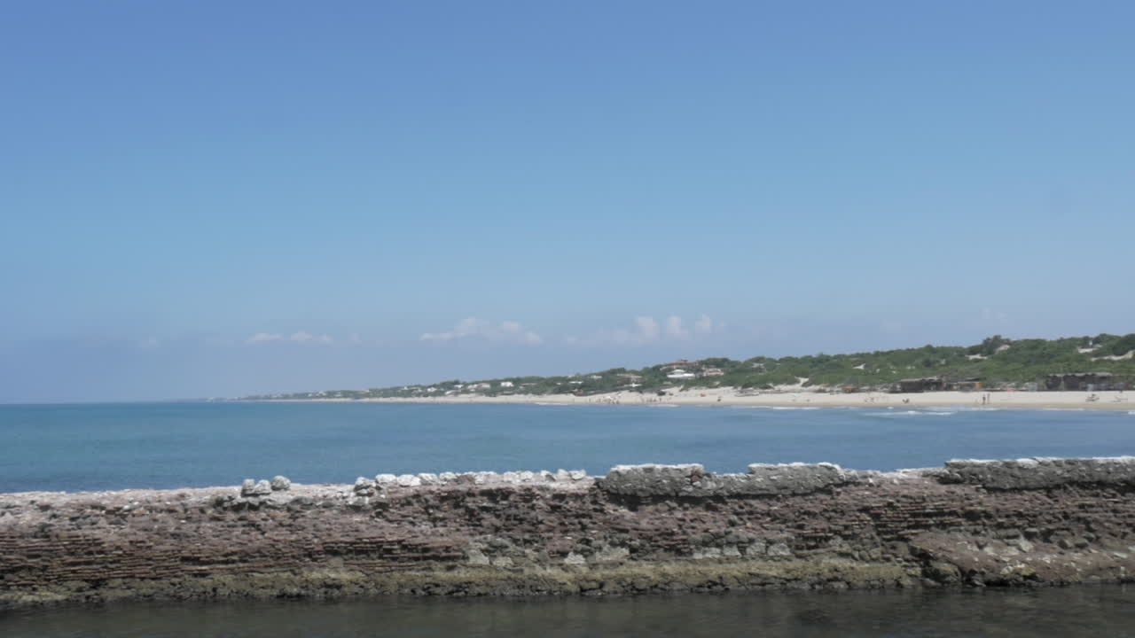 Establishing shot of the coastline near Sabaudia in Italy. Showing the entrance to the lagoon of Sabaudia.