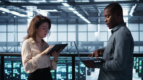 smiling admins using laptop in data center, managing server virtualization