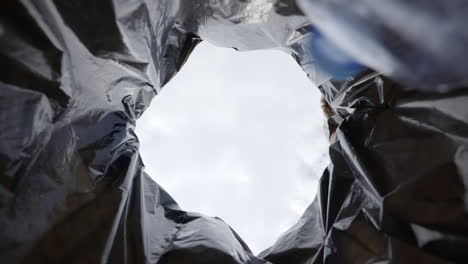 slow motion low angle view of hand dropping plastic bottle into recycling trash container