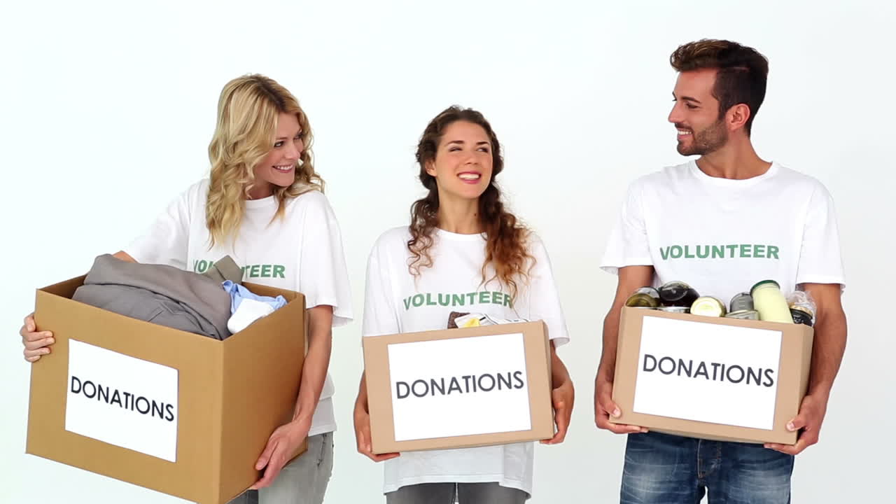 equipo de voluntarios sonriendo a la cámara sosteniendo cajas de donaciones