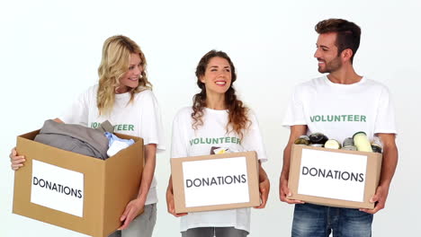 team of volunteers smiling at camera holding donations boxes