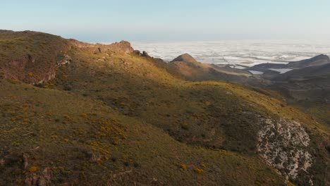 The-mountains-near-Almeria-in-the-south-of-Spain-with-in-the-background-the-greenhouses,-Aerial-shot