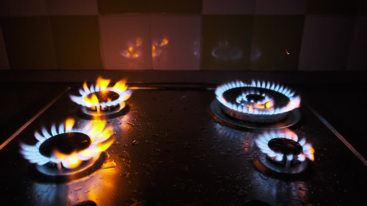 네 개의 가스 버너가 어 속에서 가스 스토브에서 동시에 불타고 있습니다.