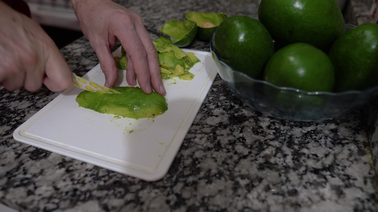 las manos masculinas cortan un aguacate orgánico en la tabla de cortar
