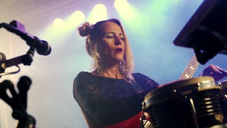 blonde girl singing and playing hand drums in nightclub close up