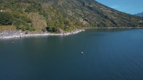 drone aerial rotating around man on a boat, paddling in lake atitlan, guatemala, central america