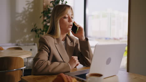 businesswoman talking on the phone while working on a laptop in a coffee shop