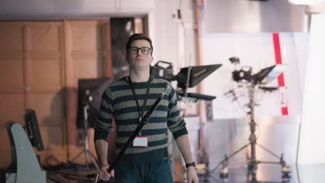 technician in broadcast studio adjusting boom pole, preparing for filming. focused on controlling equipment and positioning lighting in modern media production environment