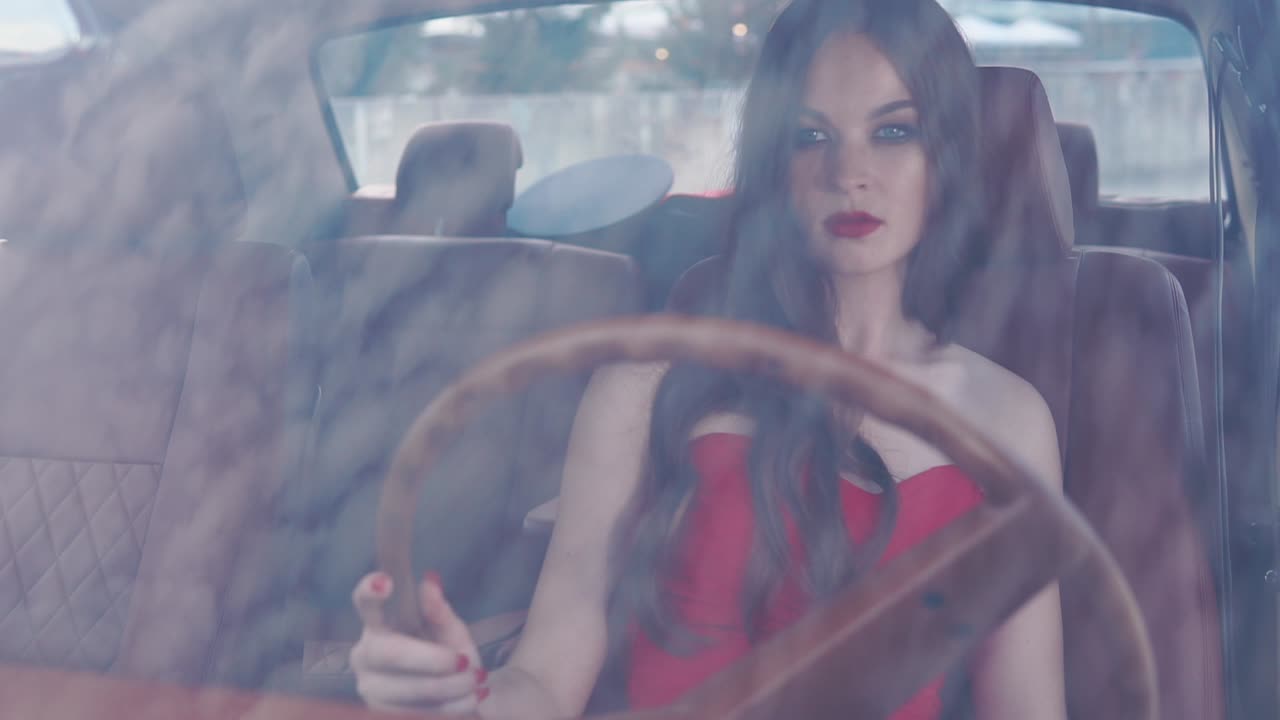Woman in a red dress driving a vintage car