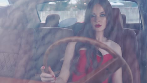 woman in a red dress driving a vintage car