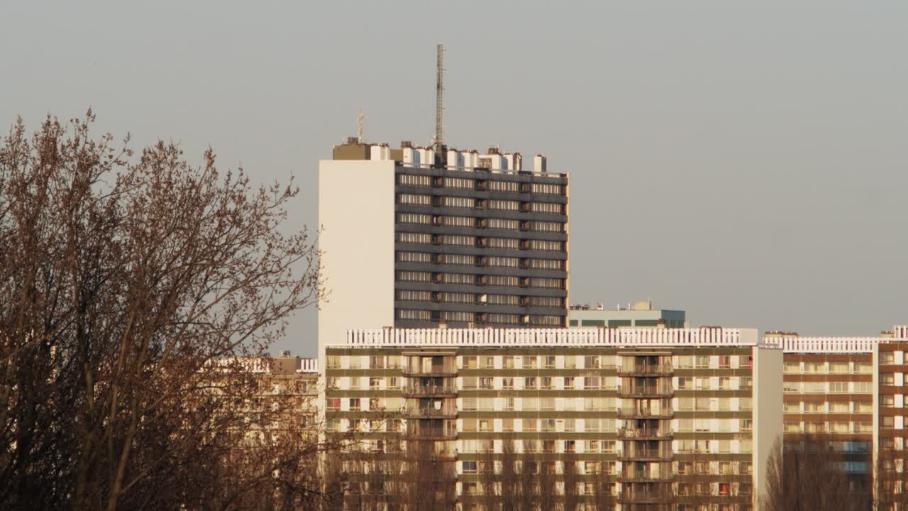Close-up view of the Chicagoblok tower and adjacent social housing blocks in Linkeroever, Antwerp, during sunset with warm light and bare trees