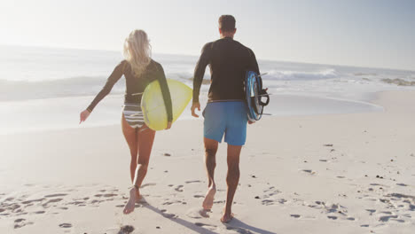 pareja caucásica con tablas de surf en la playa