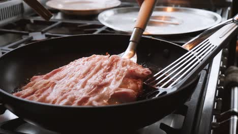 a chef cooks traditional okonomiyaki pancakes in a hot oil in a pan