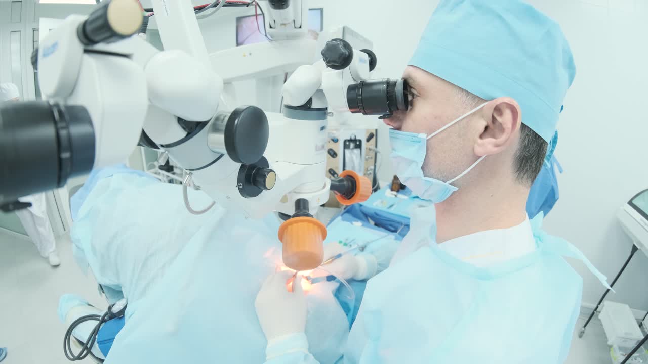 Surgeon looking into the microscope at the eye of female patient at the operating room. Doctor using microscope during eye surgery process, treatment of cataract and diopter correction.
