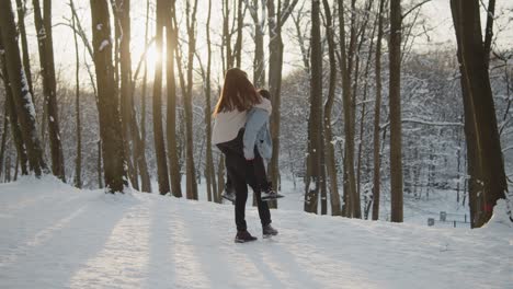 happy young beautiful couple have fun in sunny winter forest together