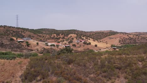 drone flying over forested valley towards farm warehouse on countryside landscape