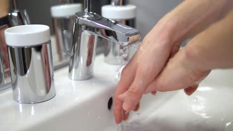 Close-up-of-white-male-washing-hands-in-sterile-bathroom