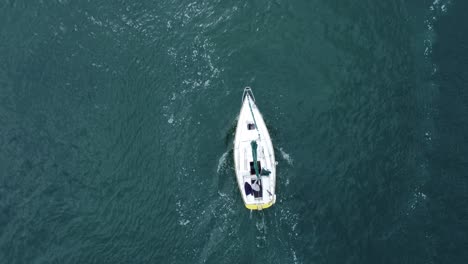 Sailing-ship-leaving-wake-navigating-River-Conwy-aerial-birds-eye-view-heading-out-of-harbour