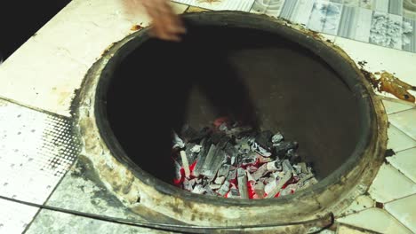 start to make the first bread the traditional way, making the oven ready with the red coal, by hitting the wall of the mud oven.