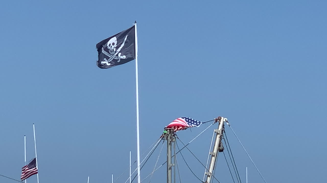 una bandera pirata ondeaba desde un asta de bandera contra un cielo azul