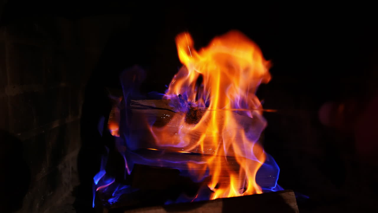 Beautiful bright fire flames. Wooden logs are burning in red and yellow fire on dark background. Close-up.